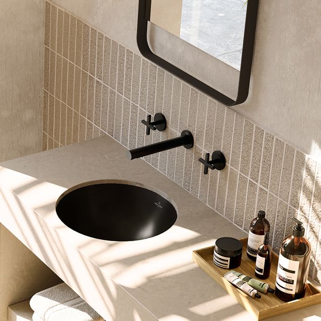 beiges Badezimmer mit schwarzen Akzenten wie Waschbecken, Armaturen, Spiegel