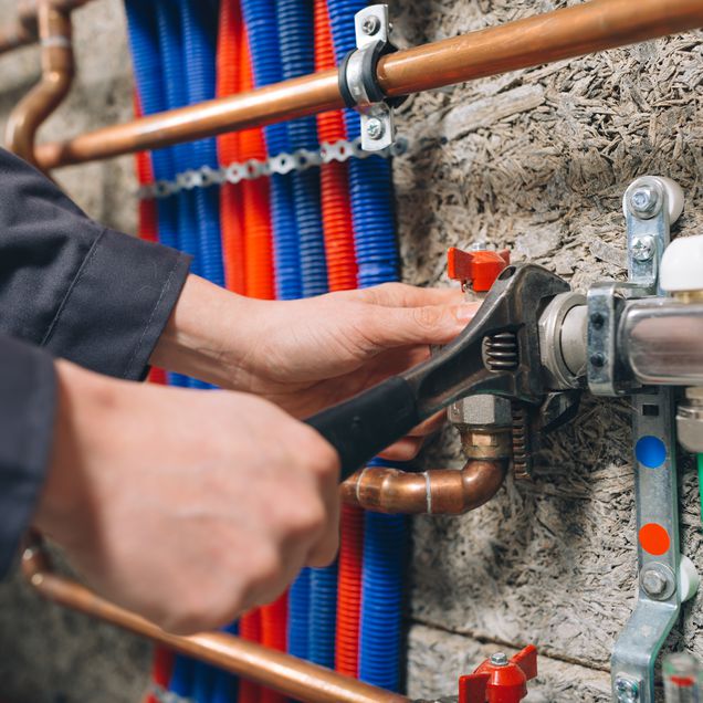 Handwerker arbeitet an Heizungsrohren.