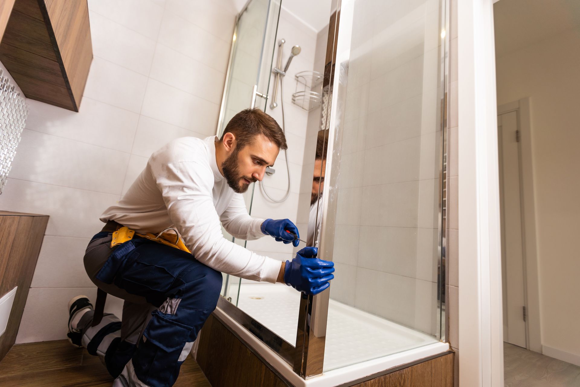 Handwerker baut eine Duschabtrennung ein.