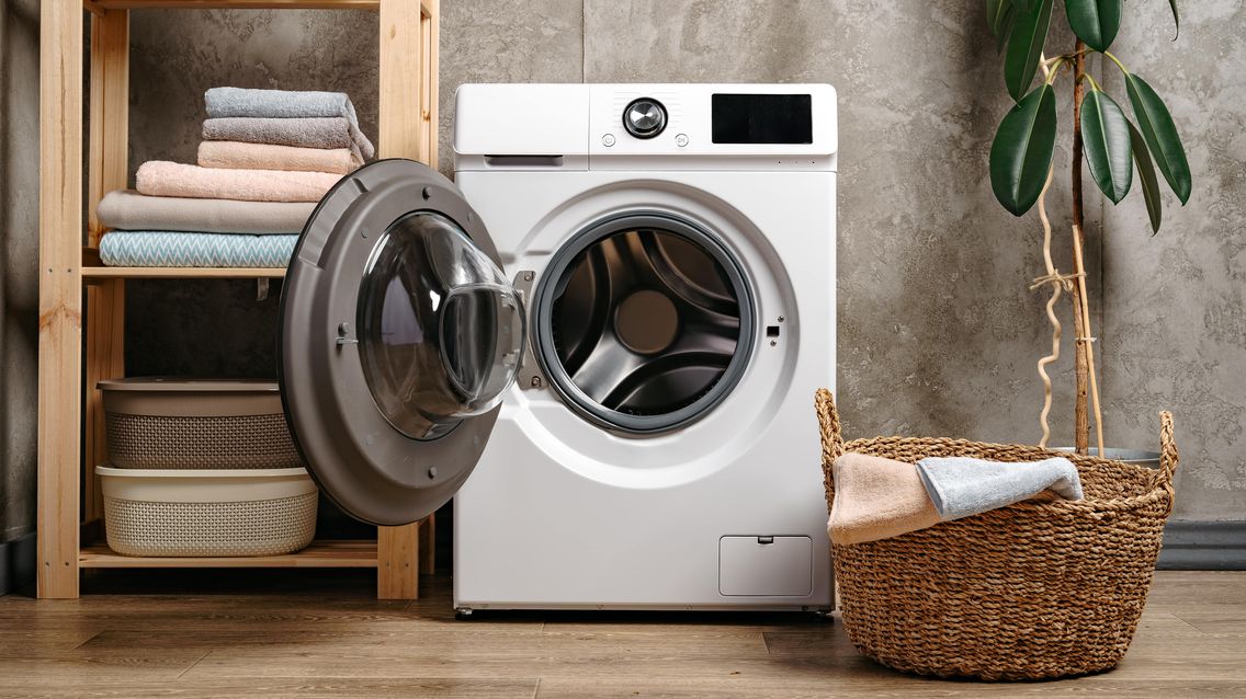 Waschmaschine mit geöffneter Tür neben Badezimmerregal.