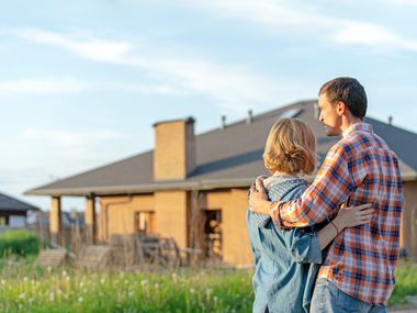 Einfamilienhaus mit umarmenden Paar im Vordergrund