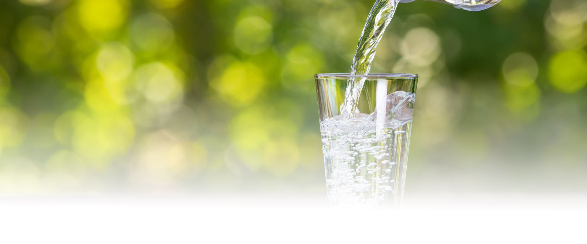 Frisches Wasser wird in ein Glas gegeossen.