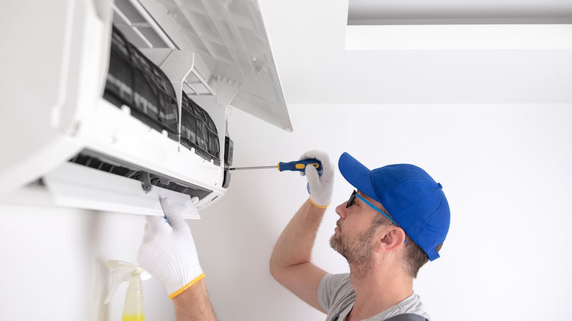 Ein Techniker wartet und reinigt die Klimaanlage
